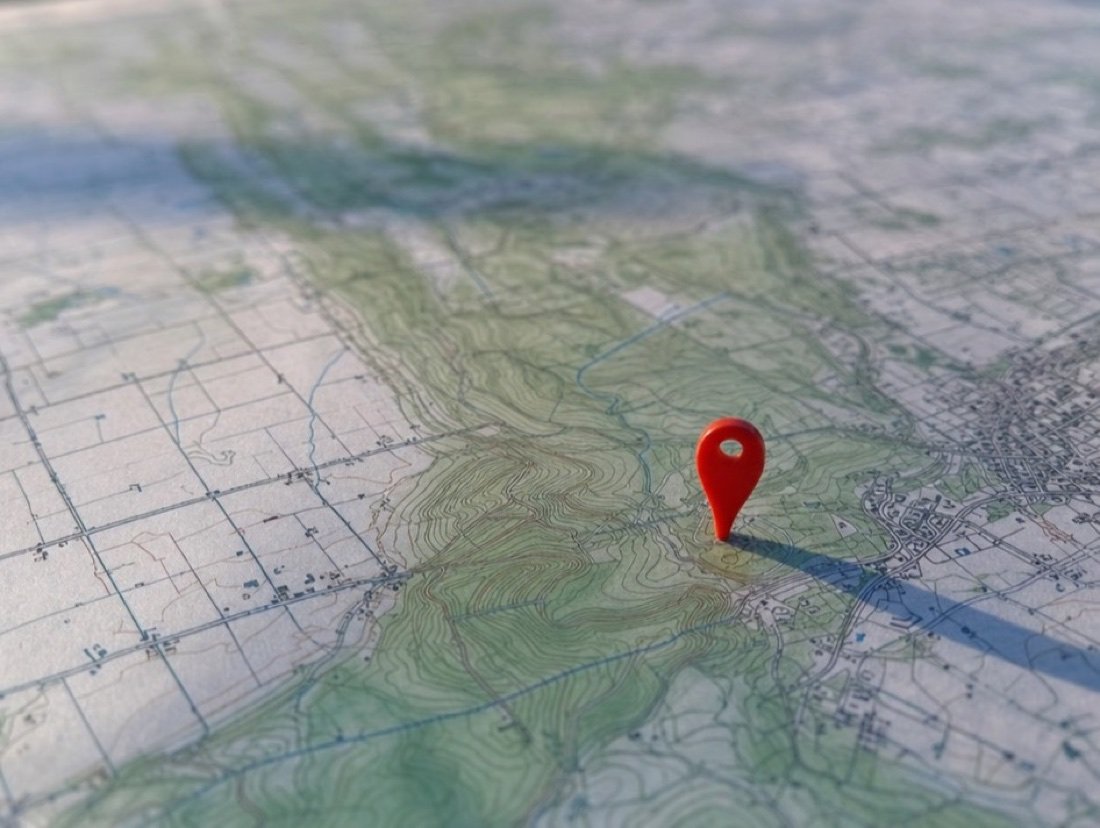 A red pin pressed into a printed topographic map