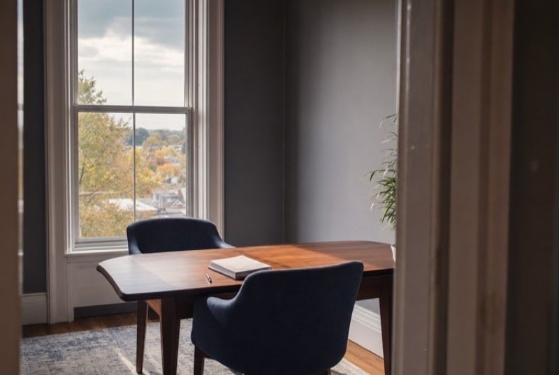 Quiet office corner set up for a meeting, chairs around a table under a tall old-style window, ready for a talk about SEO pricing